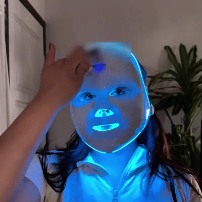 Mujer con la máscara LED puesta cambiando de luz azul a roja y verde